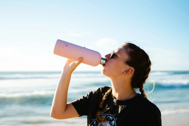 a girl drinking from a straw on the beach