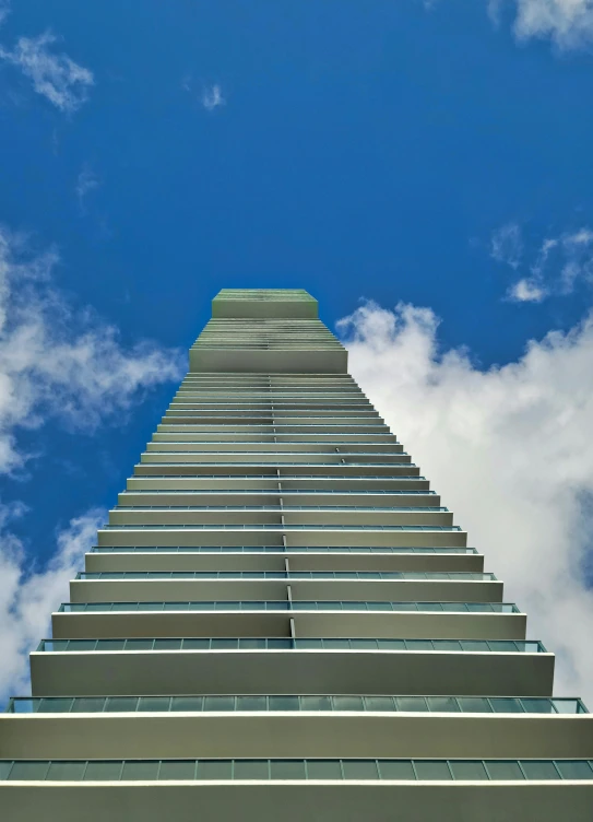 the tall skyscr with a lot of windows is against the cloudy sky