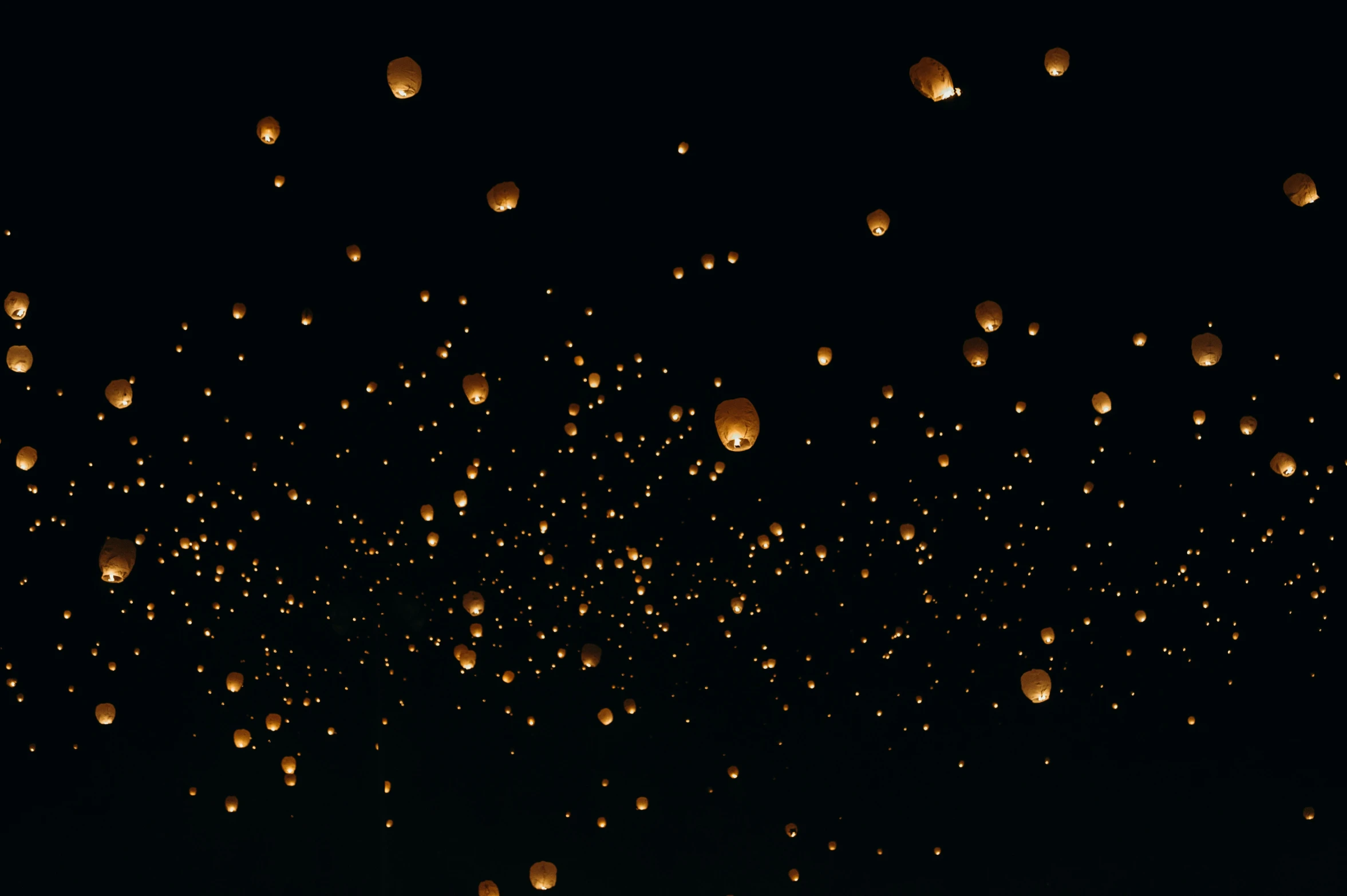 many small lanterns being lit in the dark sky