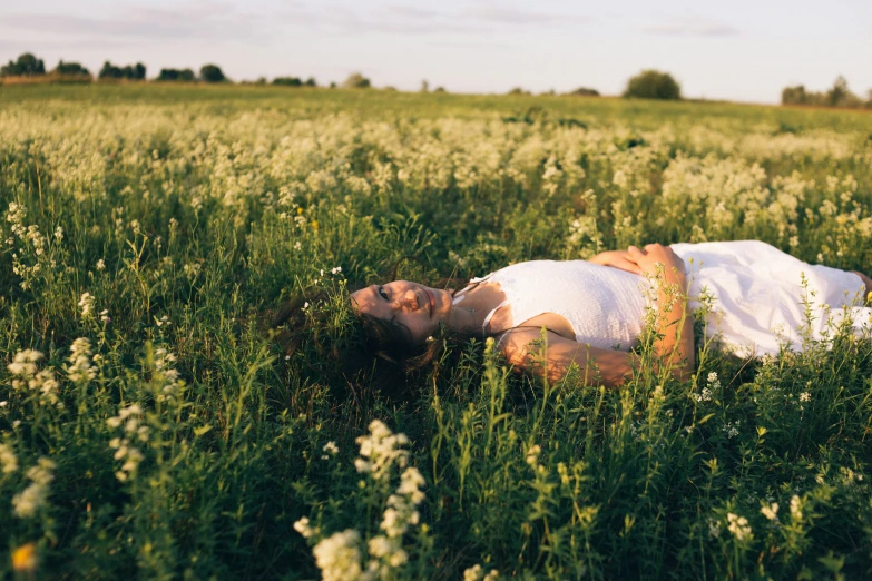 a woman is lying in the middle of a field of grass