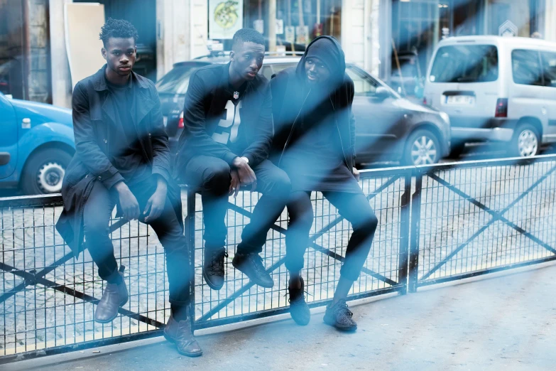 four people sitting on fenced off area with cars in back ground