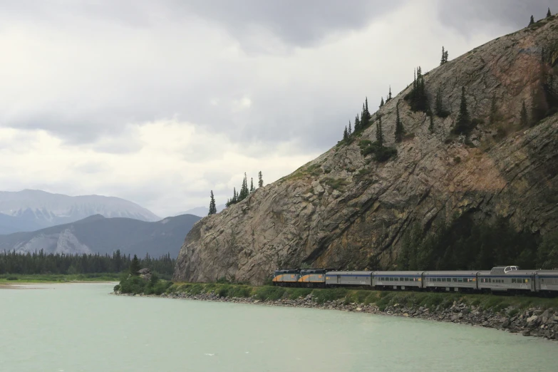 train going along a train track next to water and trees