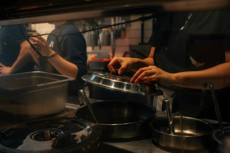 people in a kitchen preparing food with large pots