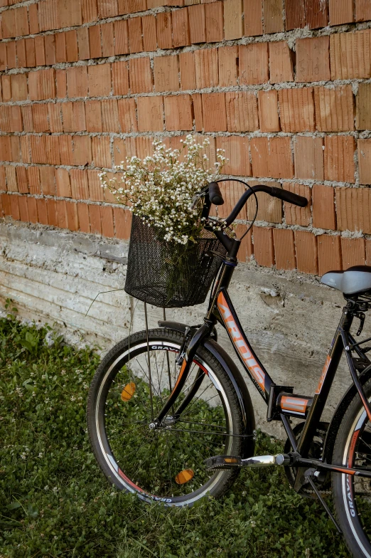 a bike with a basket on the back parked next to a brick wall