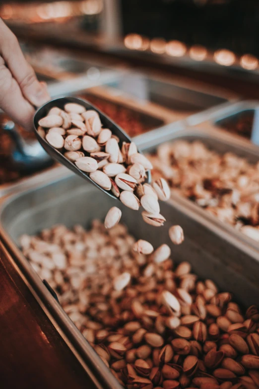 a person scooping nuts into an open pan