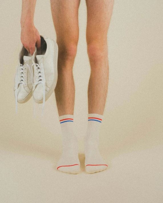 person standing in striped shorts and white tennis shoes