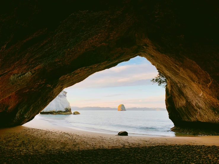 a large cave near the water on a beach