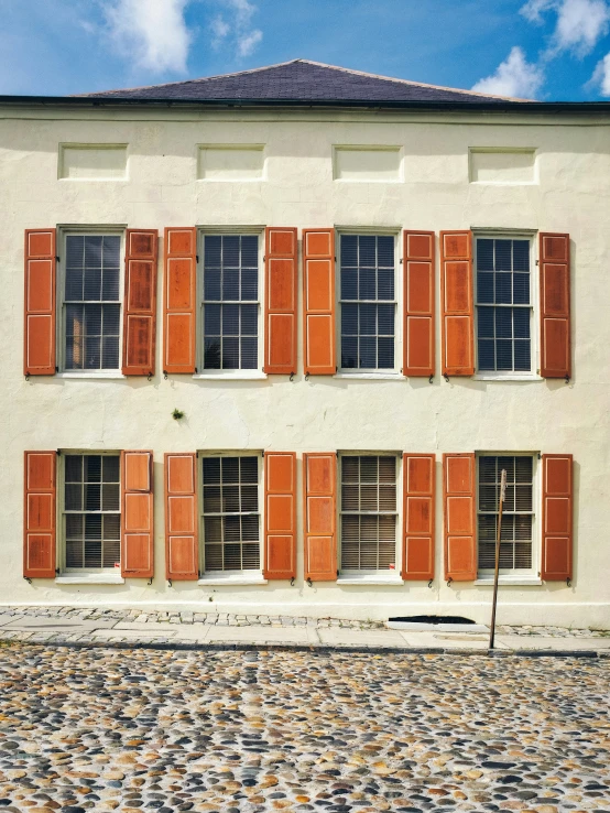 an orange shuttered window on an old house