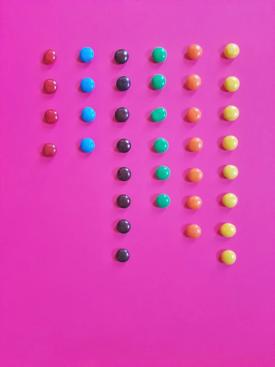 a large number of chocolate candies on a bright pink surface