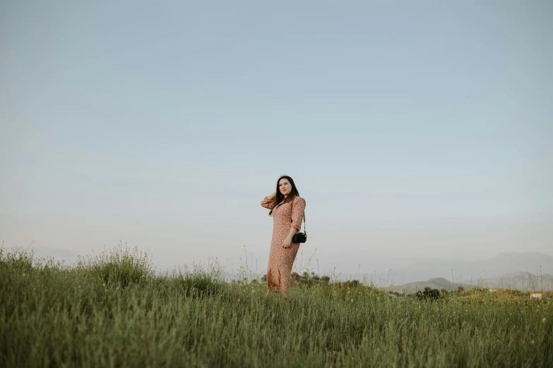 a woman in a pink and black dress is standing in a green field