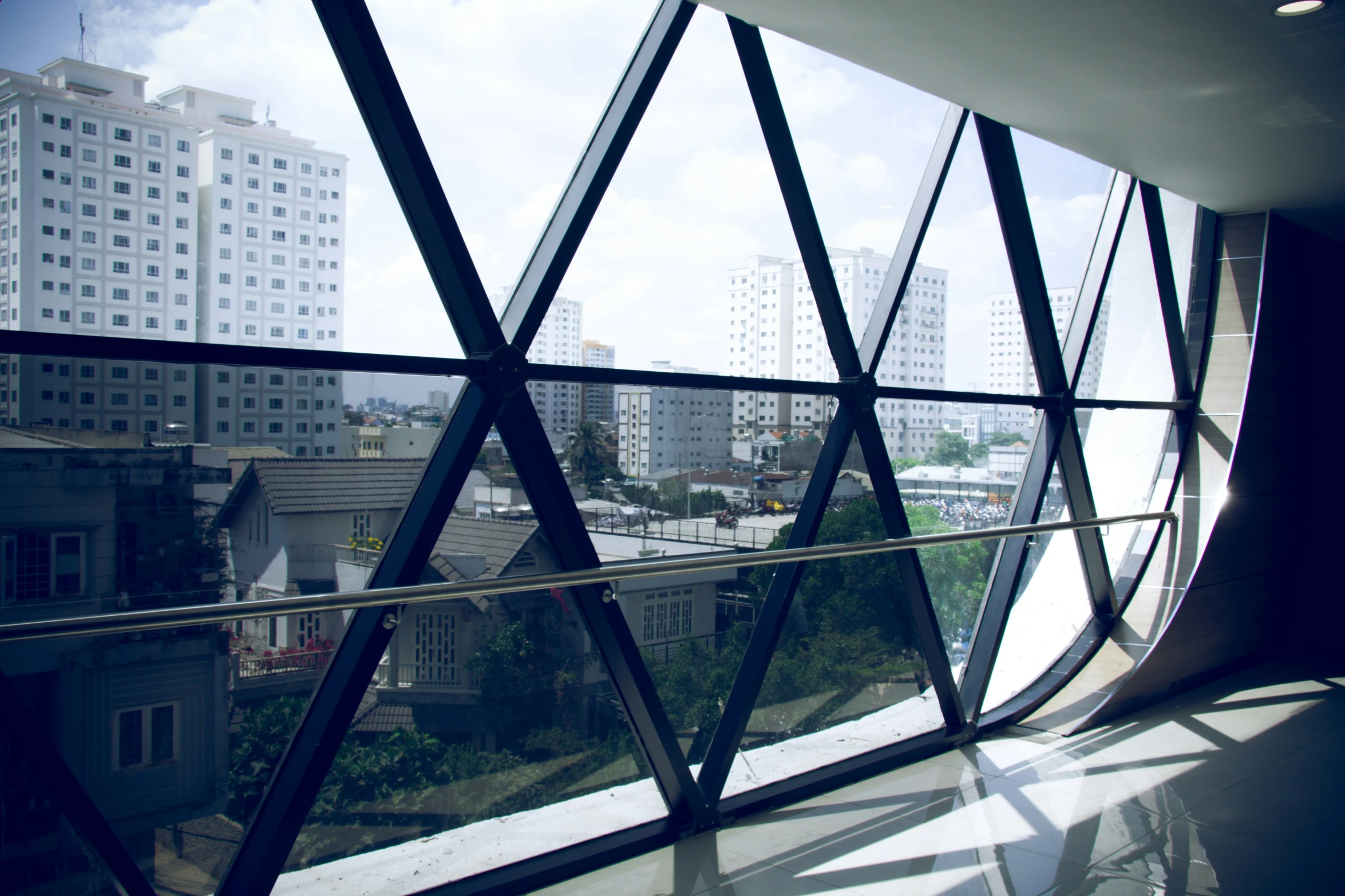 looking outside through a triangular glass door at some buildings