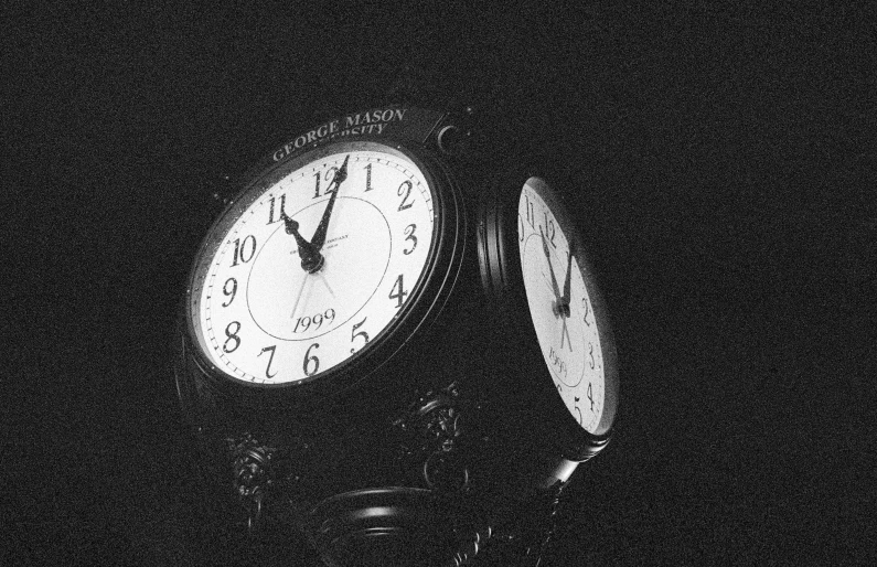 two clocks in the dark with their hands pointing in the opposite direction