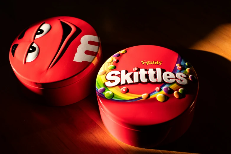 a pair of skittles and a cookie tin with a face and tongue