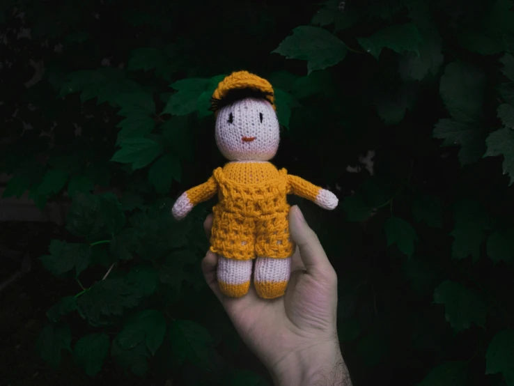 there is a small stuffed toy wearing a yellow sweater