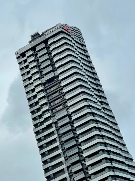 a tall building against a cloudy sky with an airplane flying overhead