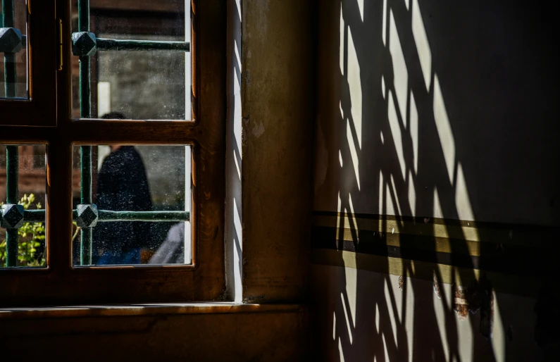 a window showing through a wooden building with a view of someone standing outside