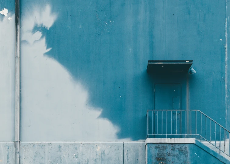 a staircase next to a blue wall in front of an open window