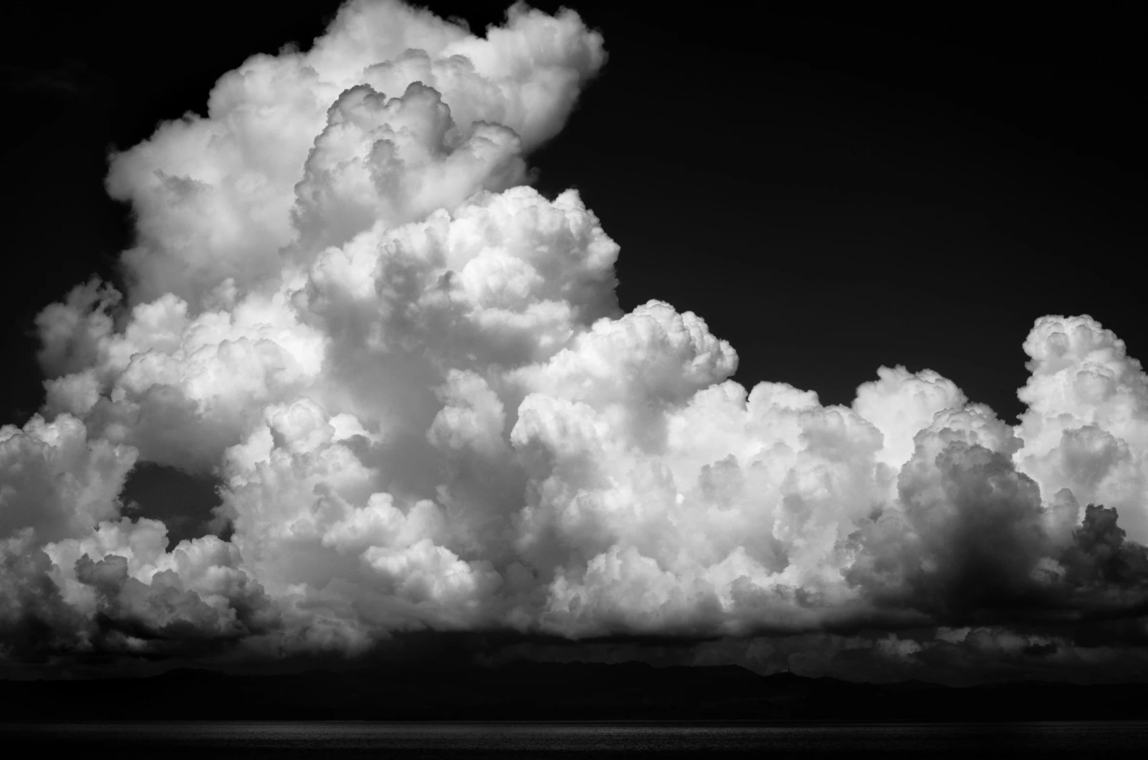 the clouds hover above a body of water on a clear day