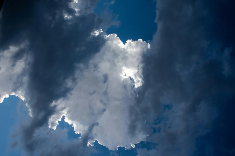 the blue sky with clouds and a plane in the distance