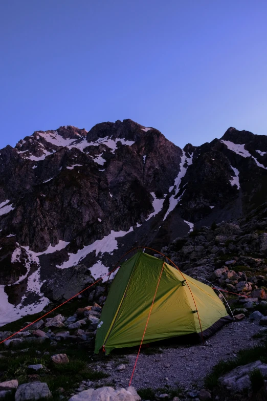 a tent pitched up on the ground with a mountain in the background