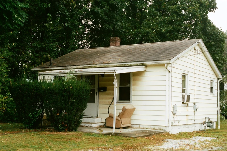 a little white building with some windows sitting next to trees