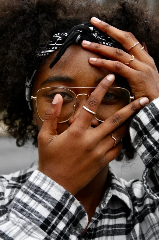 a woman wearing glasses holding her hands to her face