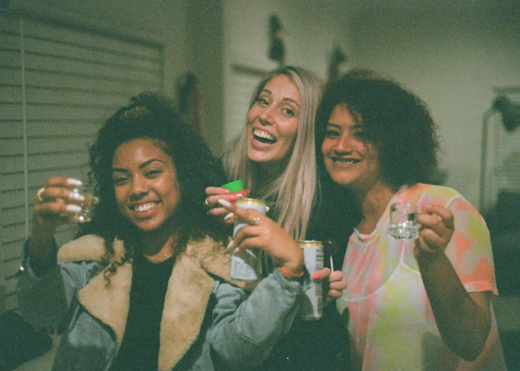 three women holding drinks in each others hands