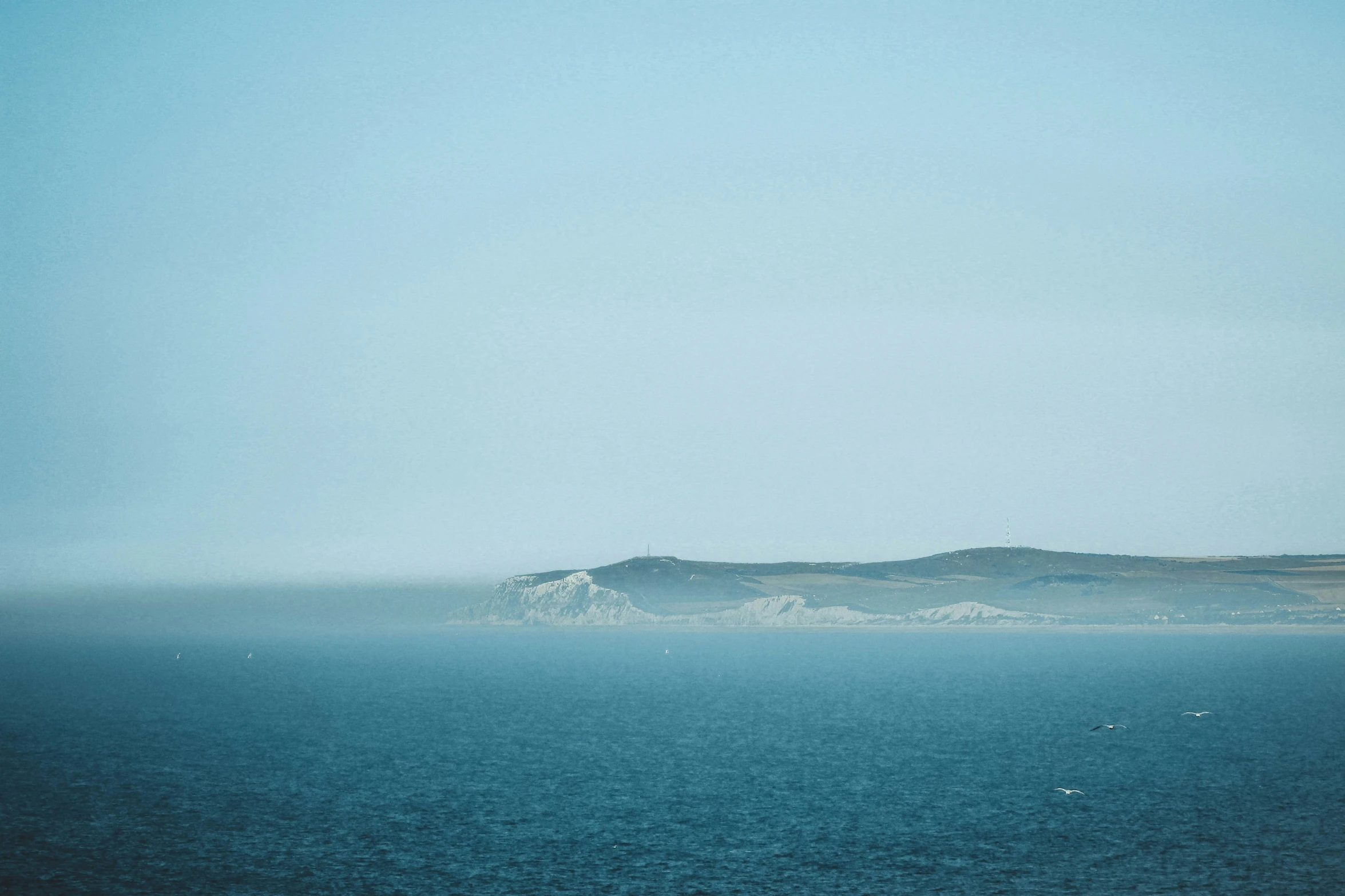 blue ocean with white island in the distance