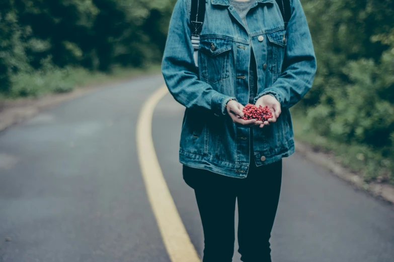 a young woman holding a flower in her hands while walking on a path