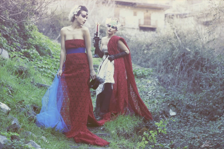 two women in gowns standing on a hill