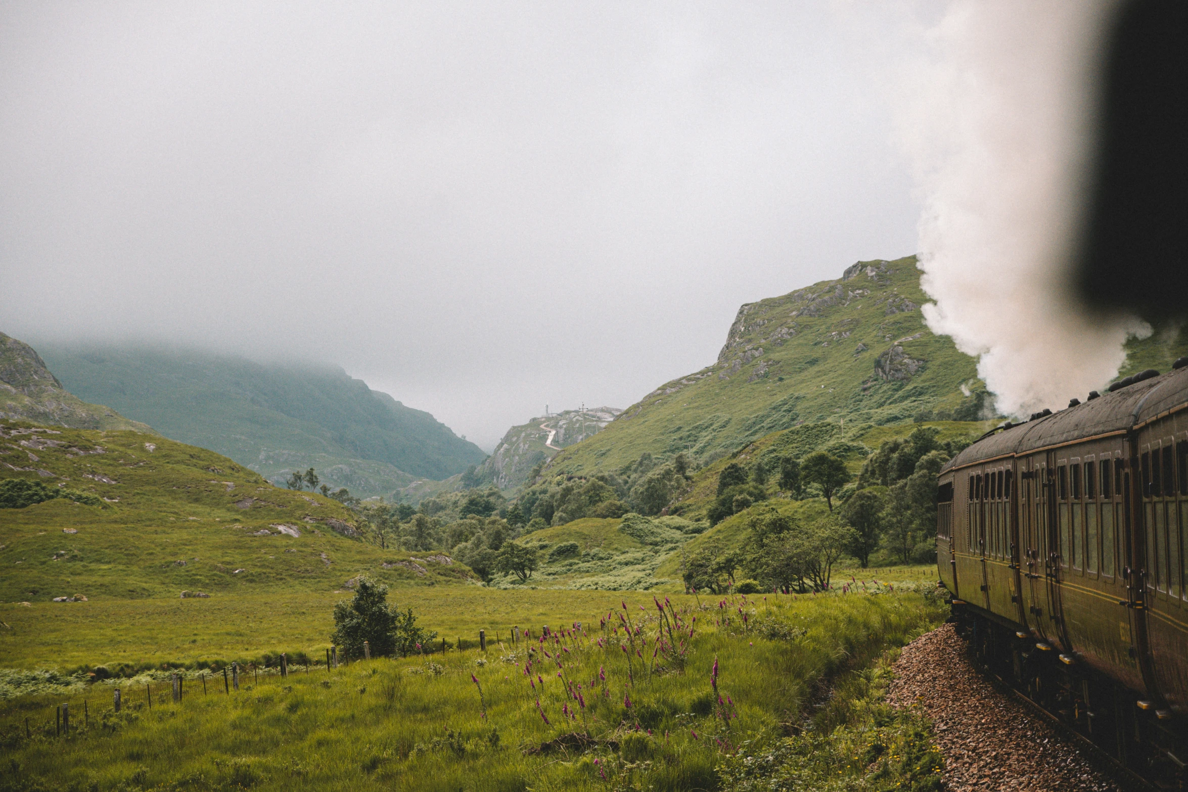 there is an old train moving on the tracks near mountains