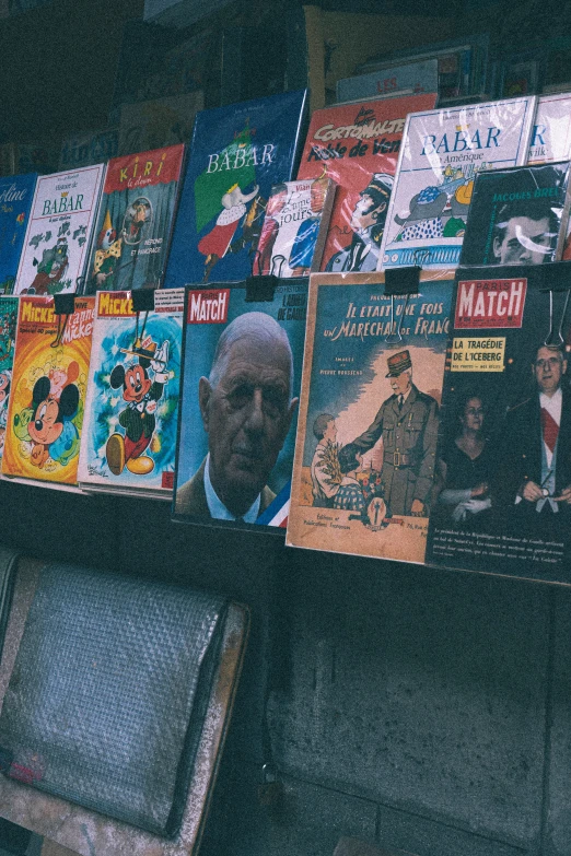 old man reading magazine next to bookshelf with posters