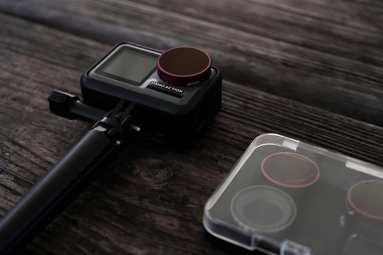 a camera next to a small plastic container on a table