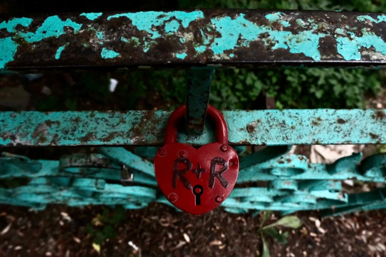 a red heart lock hanging on a metal piece