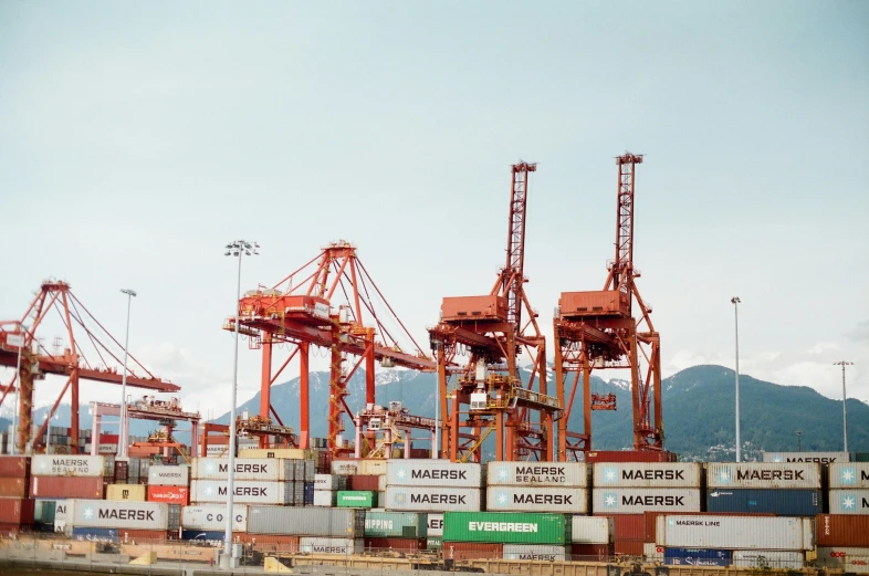 large shipping containers are in the water near mountains