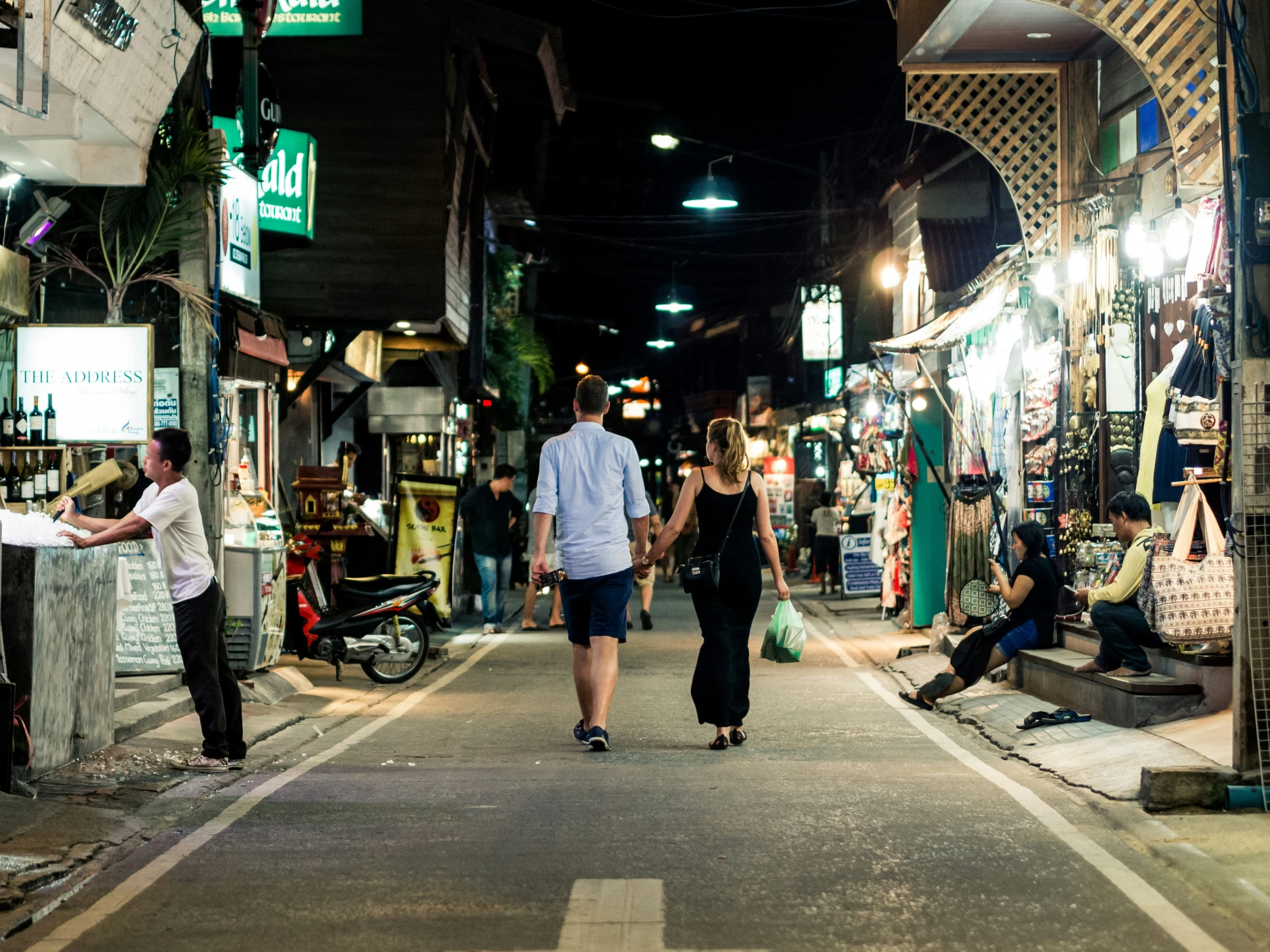 people are shopping in an outdoor market at night