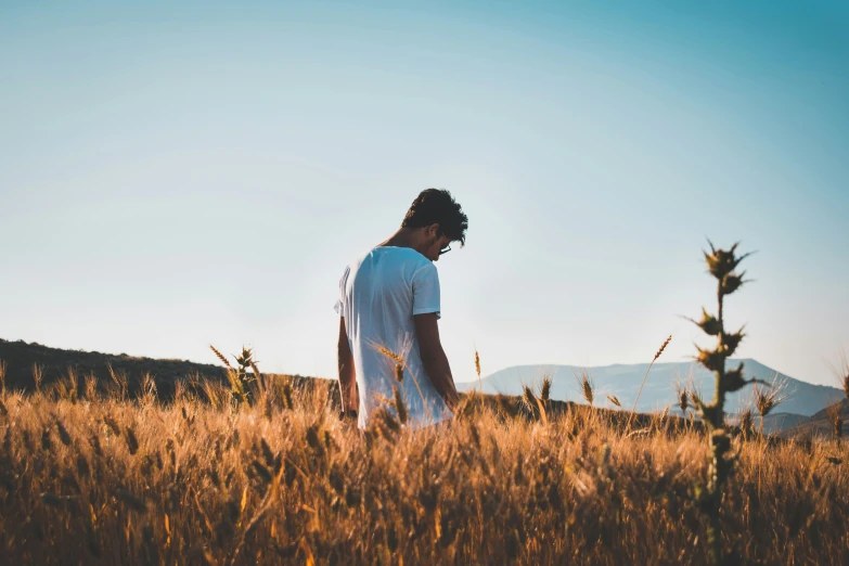 a man standing in tall grass on top of a field