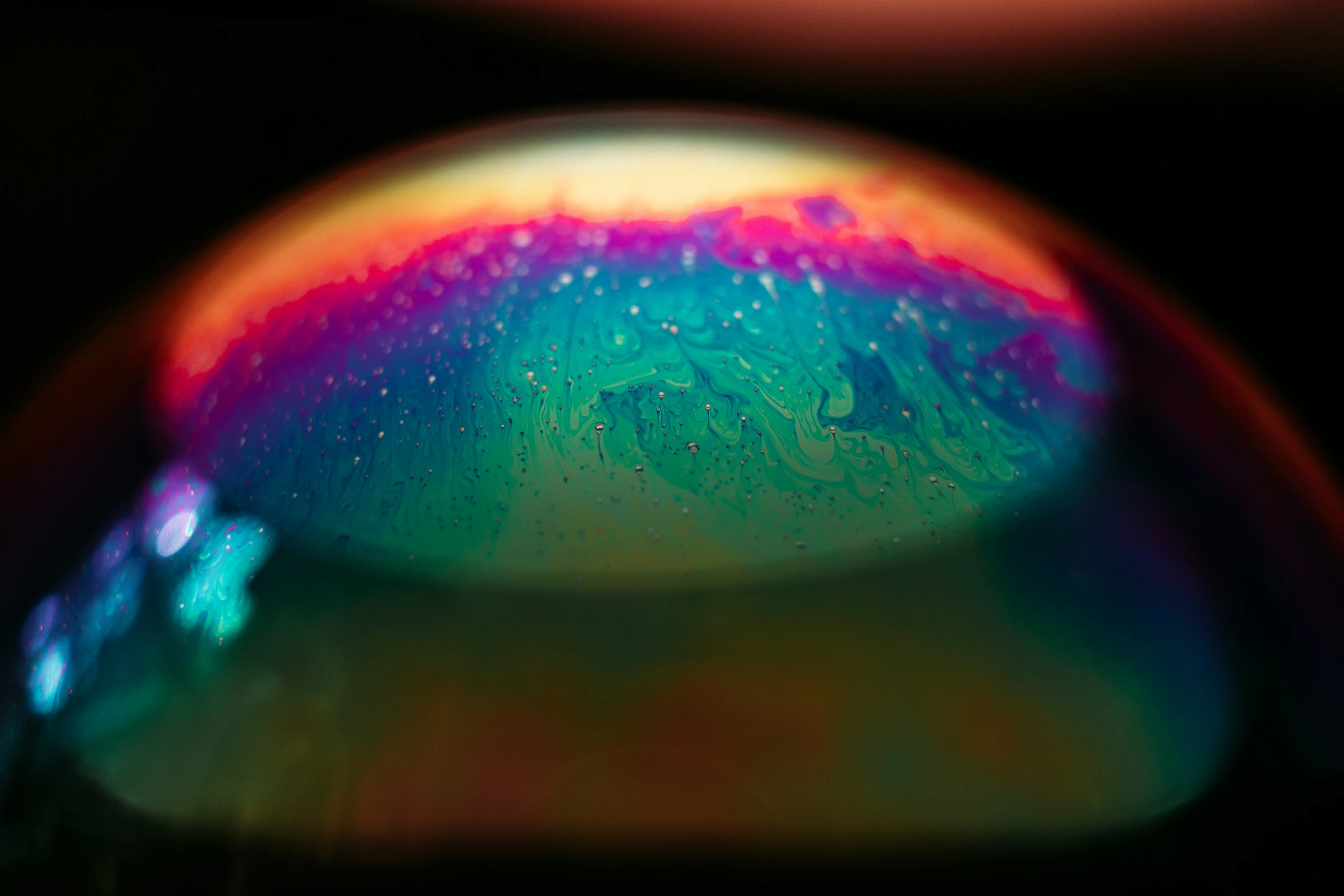 closeup image of a water droplet with rainbow colored bubbles