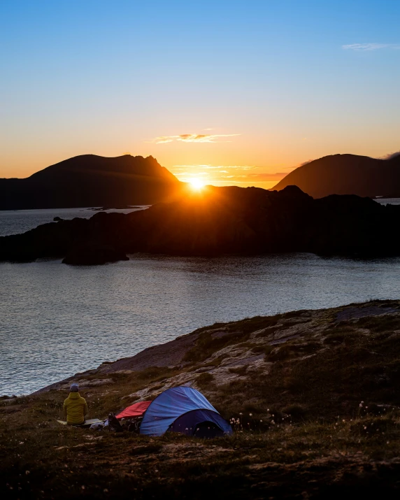 a camping tent is next to a body of water