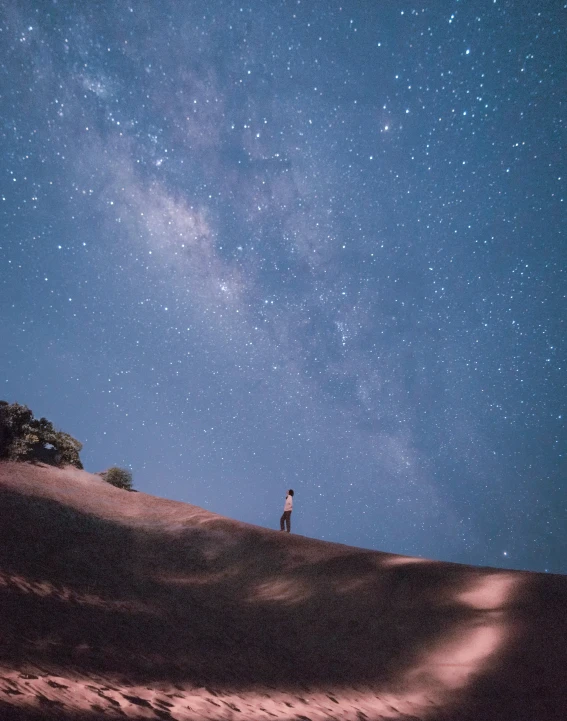 two people standing on a dune in the night sky with stars in the background