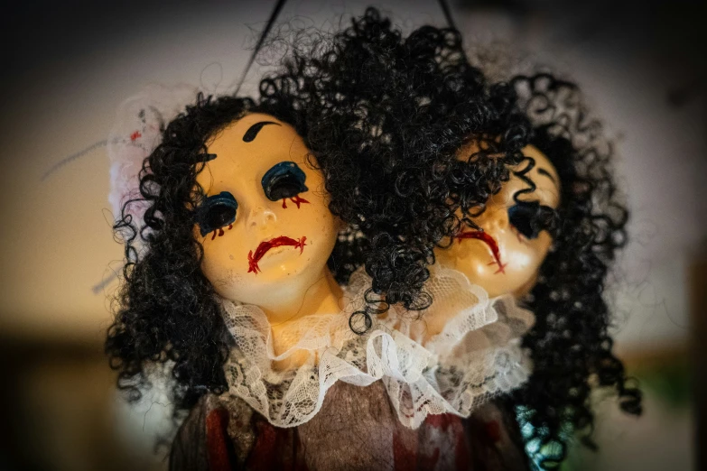 three creepy dolls with dark black hair hanging from a hook