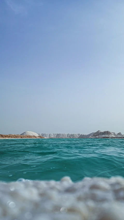 a view of an ocean, with two hills in the distance