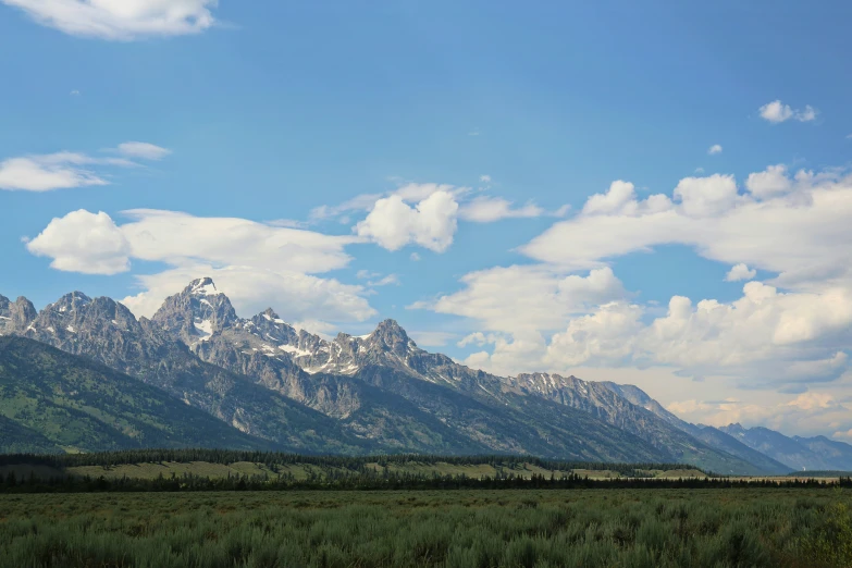 mountains and the plains beneath a blue sky with white clouds