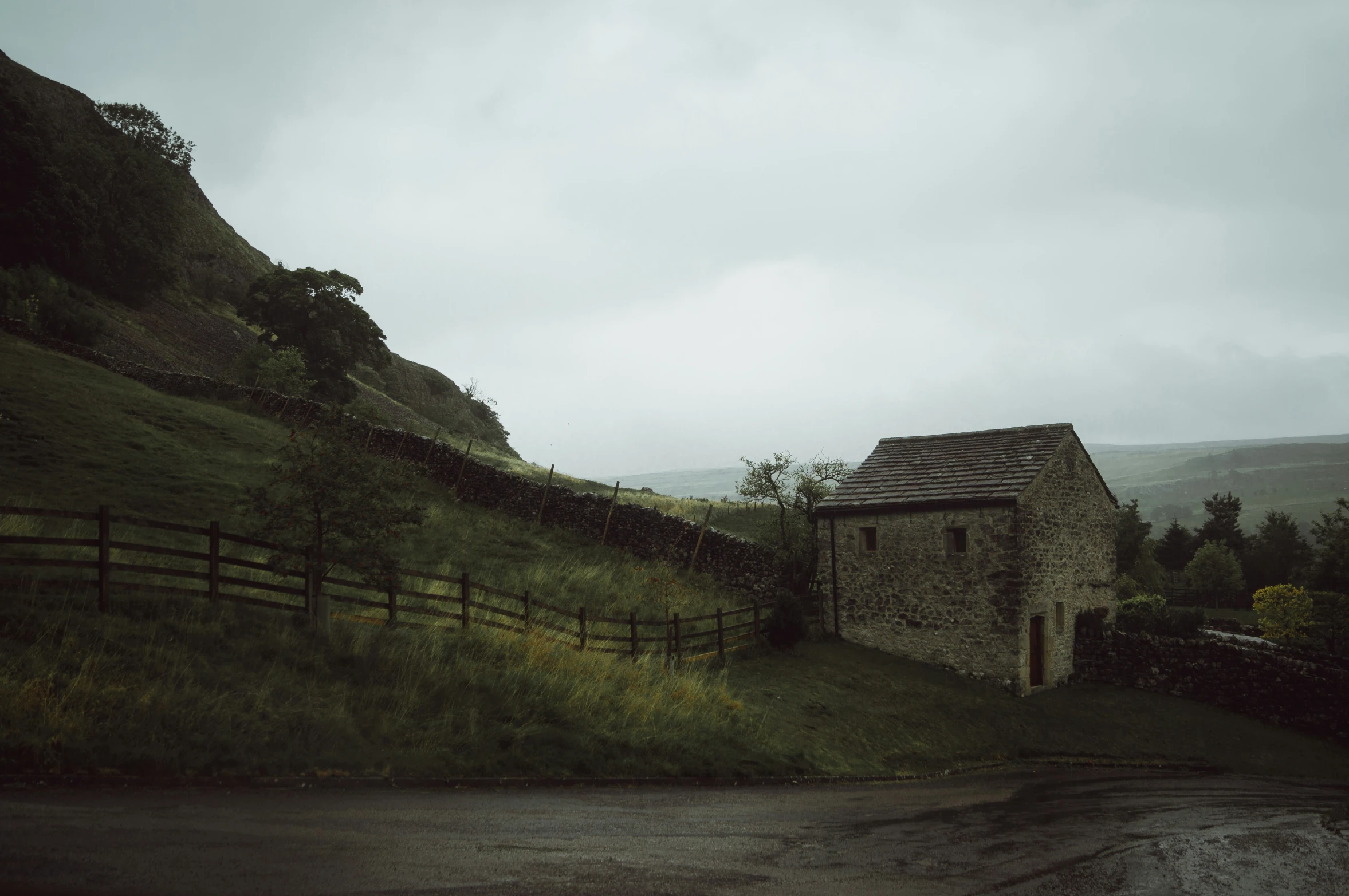 a stone cottage on the side of a hill in the rain