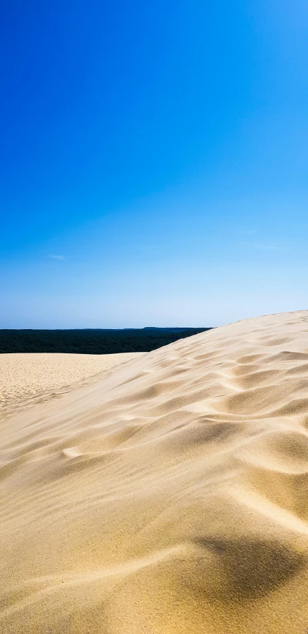 the sky is blue, but there is a white sand dune