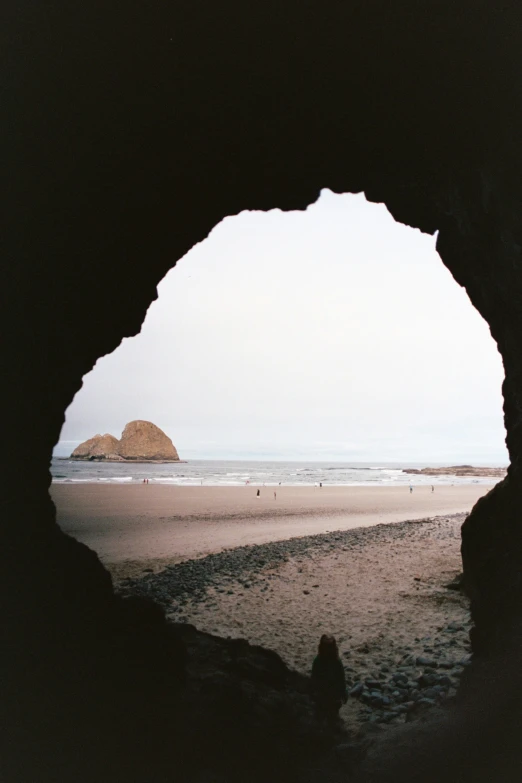 the view of the ocean through an archway in the sand