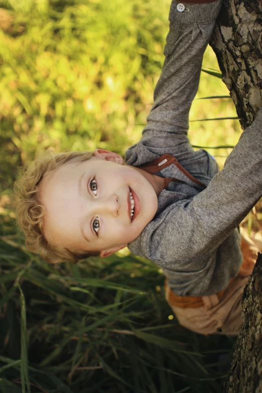 a little girl climbing up a tree with grass