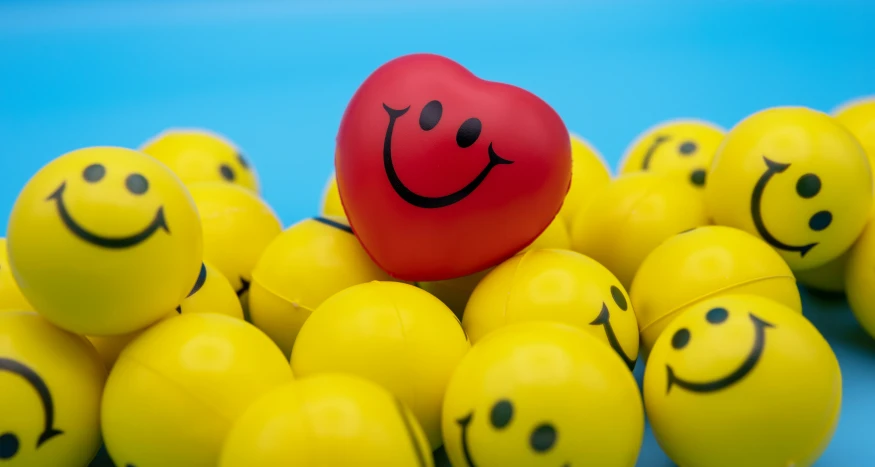 a heart surrounded by yellow balls with smiley faces on them
