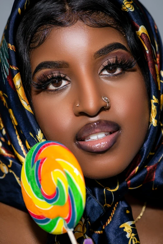a woman wearing a headscarf holding a lollipop