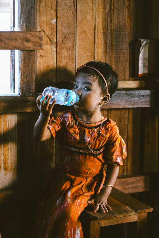 a small girl drinking out of a bottle